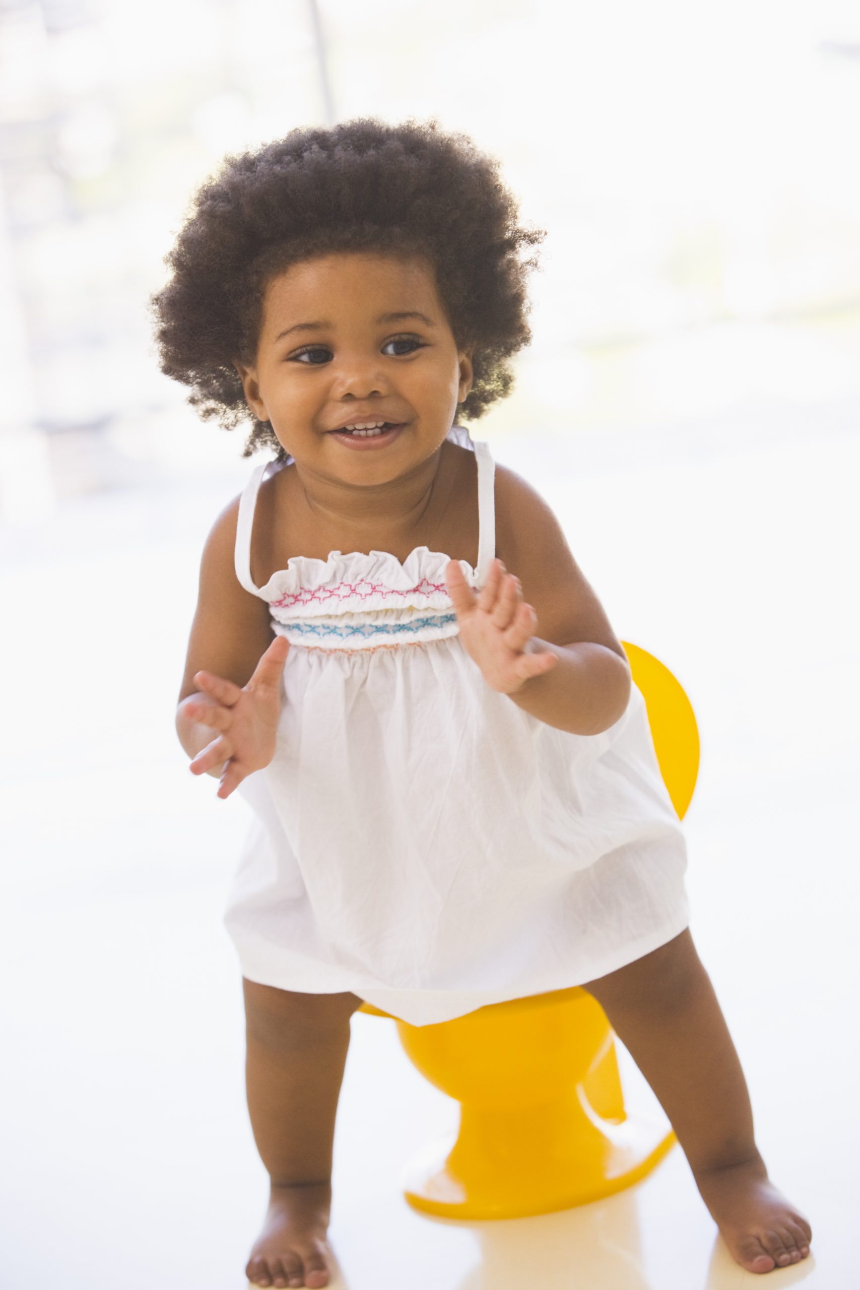 African-American girl smiling in front of a yellow potty training chair