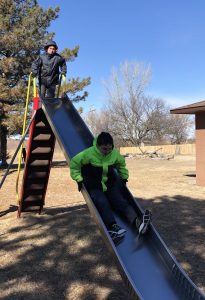 two kids one a playground slide