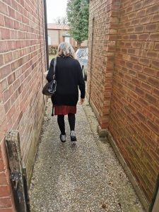 older woman walking down a brick alleyway