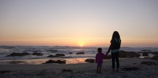 mom and daughter holding hands on a beach