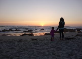 mom and daughter holding hands on a beach