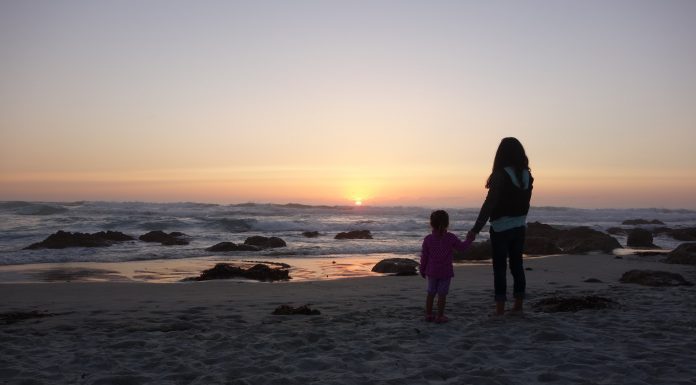 mom and daughter holding hands on a beach