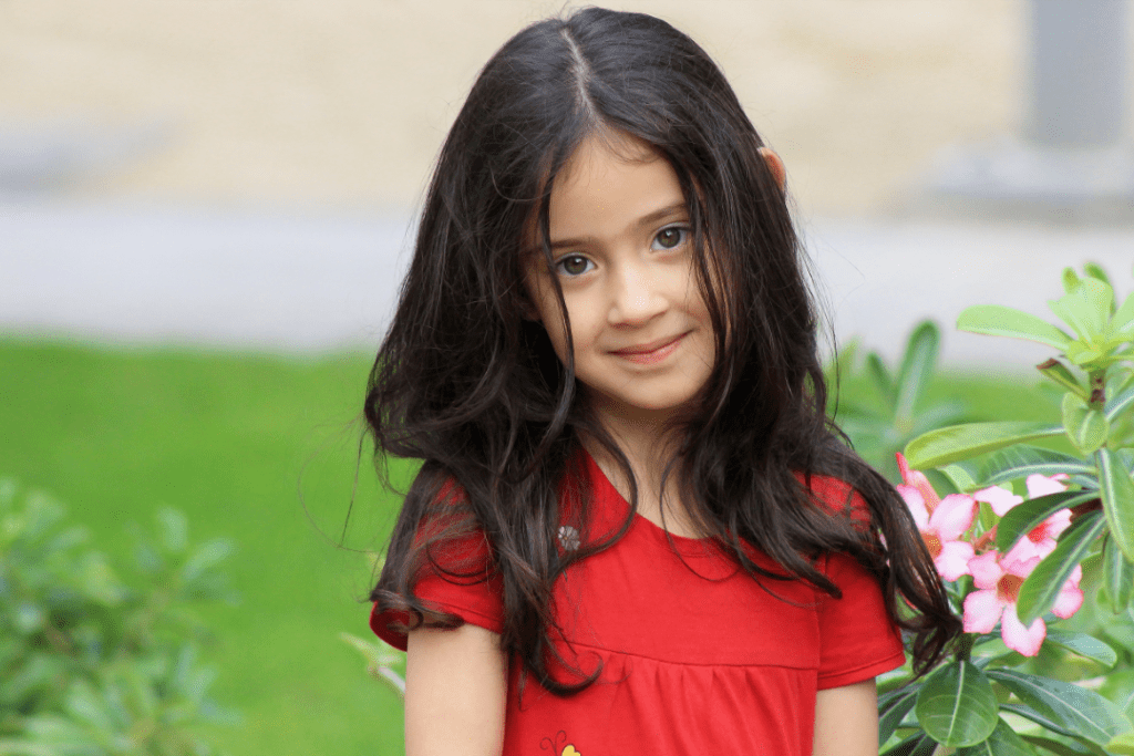 small girls standing with flowers in a field