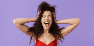 The “B” Word I Won’t Use woman standing with hands on head and looking overwhelmed on lilac background