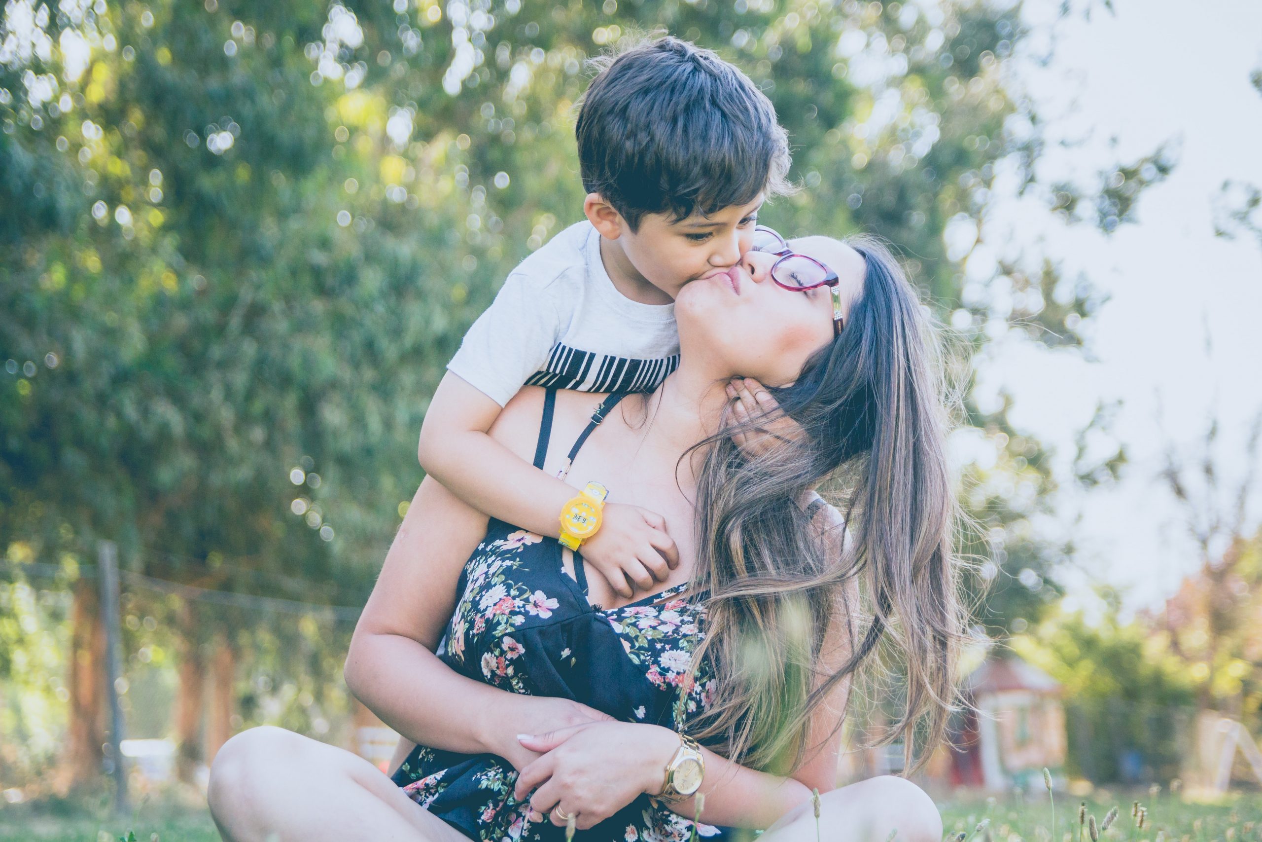 mother kissing son in a sunny field