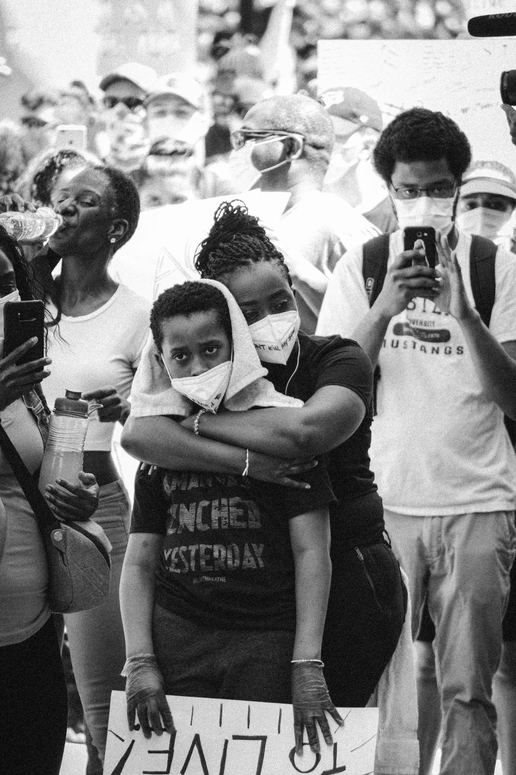 Black mother hugging son in a crowd