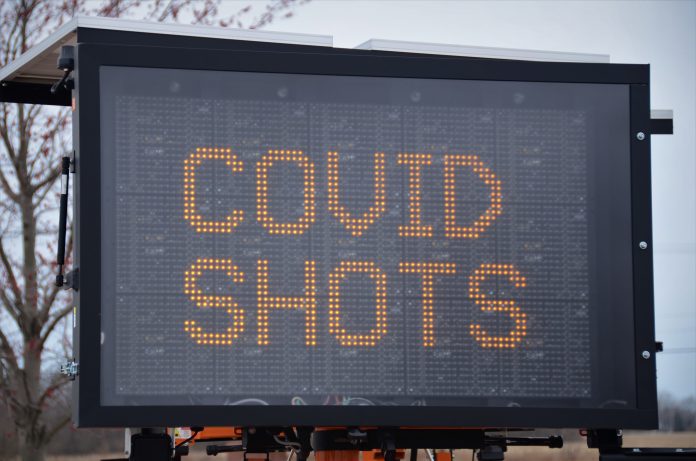 large letter board with "COVID SHOTS" on screen