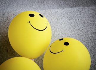 three yellow balloons with smiley faces on them