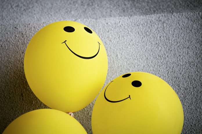 three yellow balloons with smiley faces on them