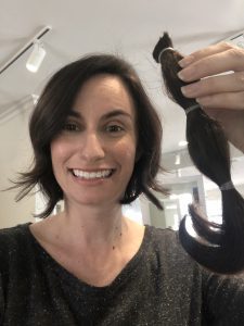 Alexandra holds her ponytail after cutting her hair short.