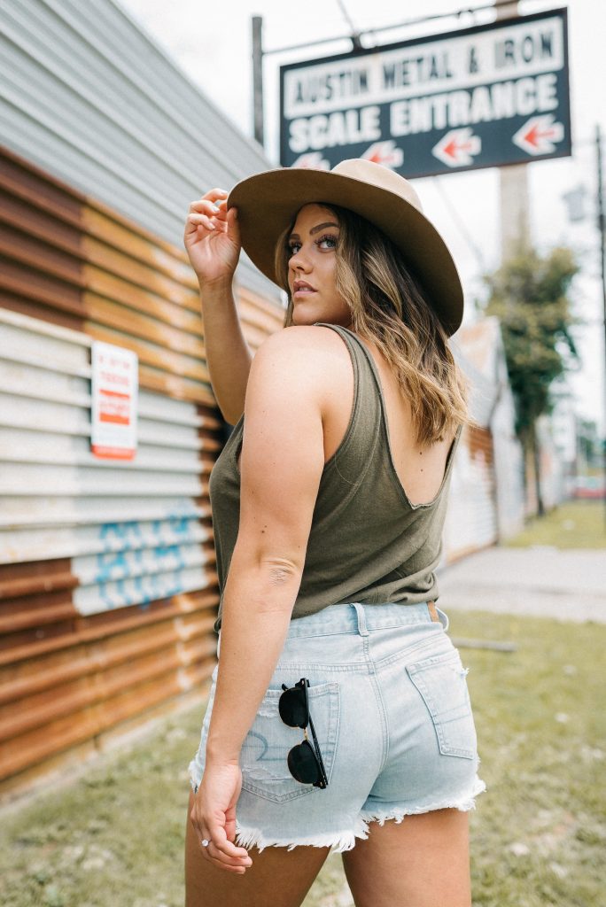 woman wearing shorts and hat with sunglasses outdoors