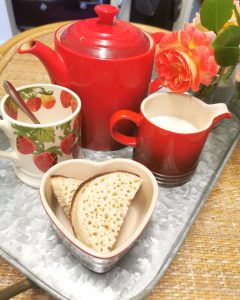 red teapot with tea cups and small sandwiches