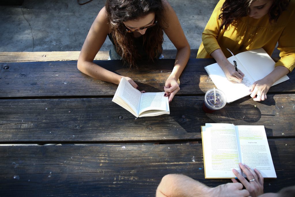 teen girls writing in notebooks on wooden table