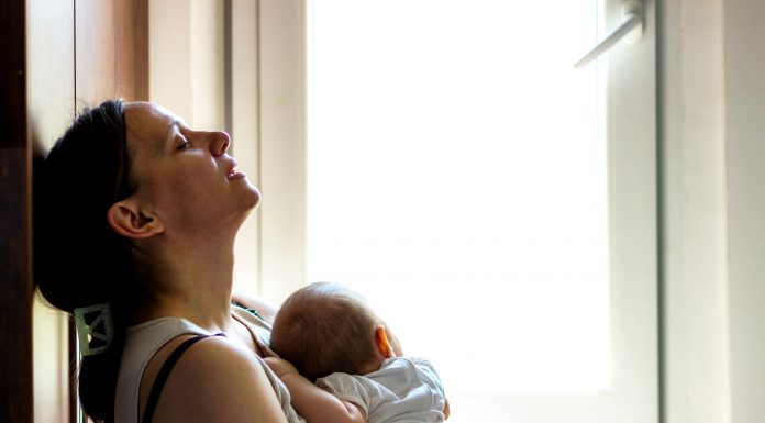 Woman holding infant appearing tired, concerned, sad, depressed