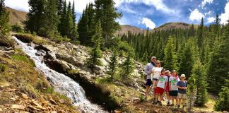 family standing next to a waterfall in the mountains