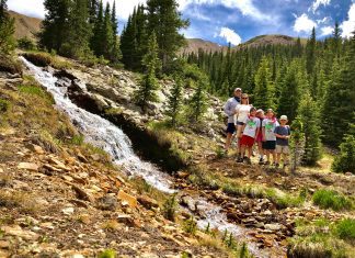 family standing next to a waterfall in the mountains