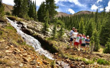 family standing next to a waterfall in the mountains