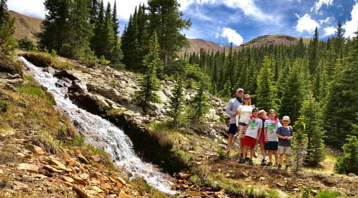 family standing next to a waterfall in the mountains