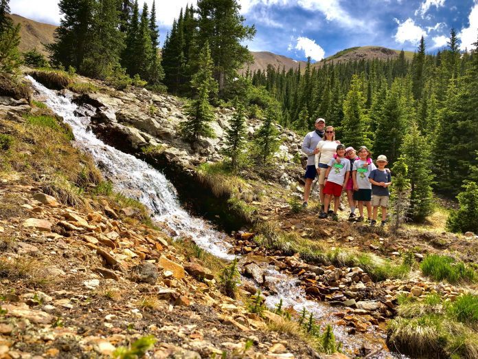 family standing next to a waterfall in the mountains