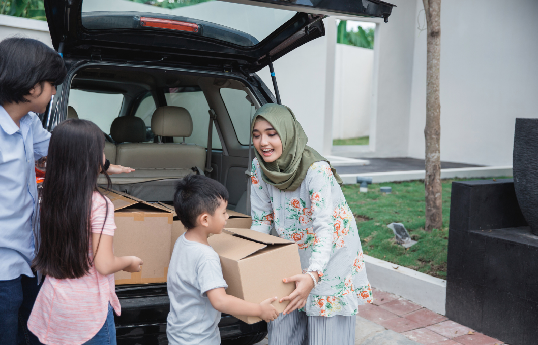 woman in hijab with children unloading moving boxes from a car