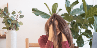 woman with head in her hands, surrounded by plants