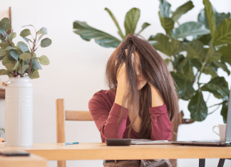 woman with head in her hands, surrounded by plants