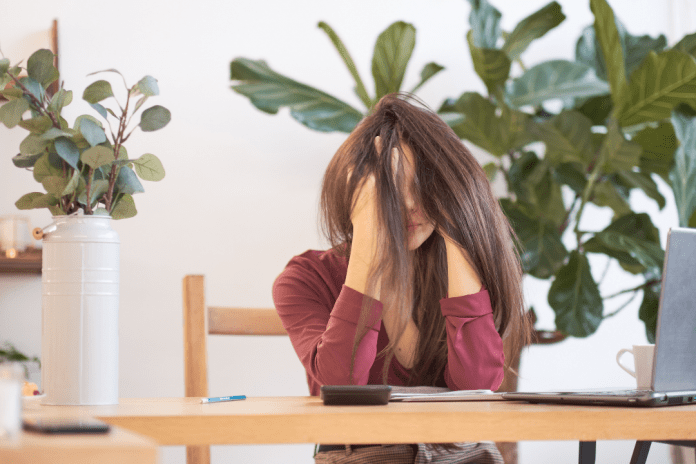 woman with head in her hands, surrounded by plants