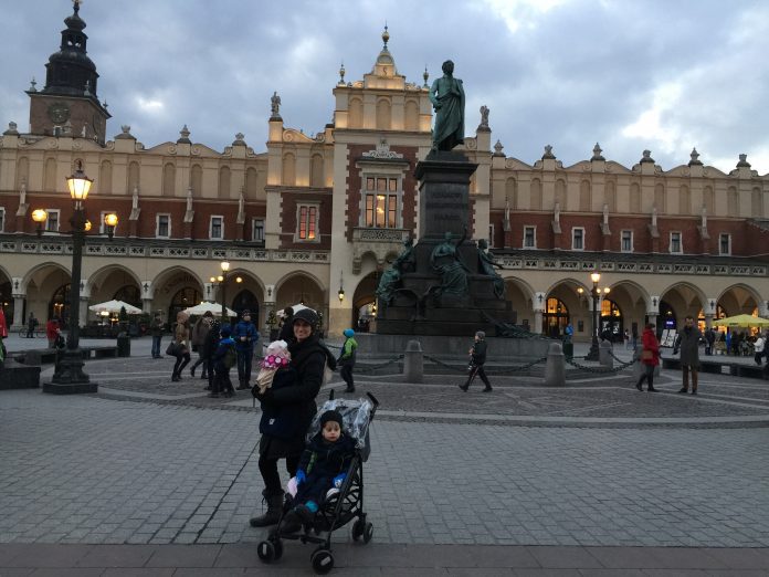 Mother and children standing in the main square of Krakow, Poland 2016