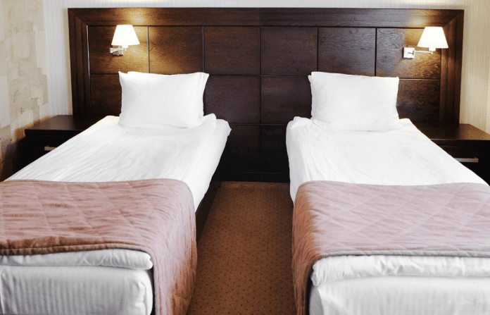 Two beds two beds in the same room with a dark wood headboard