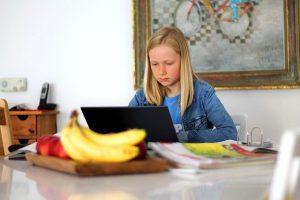 Girl sitting at a counter at home doing schoolwork