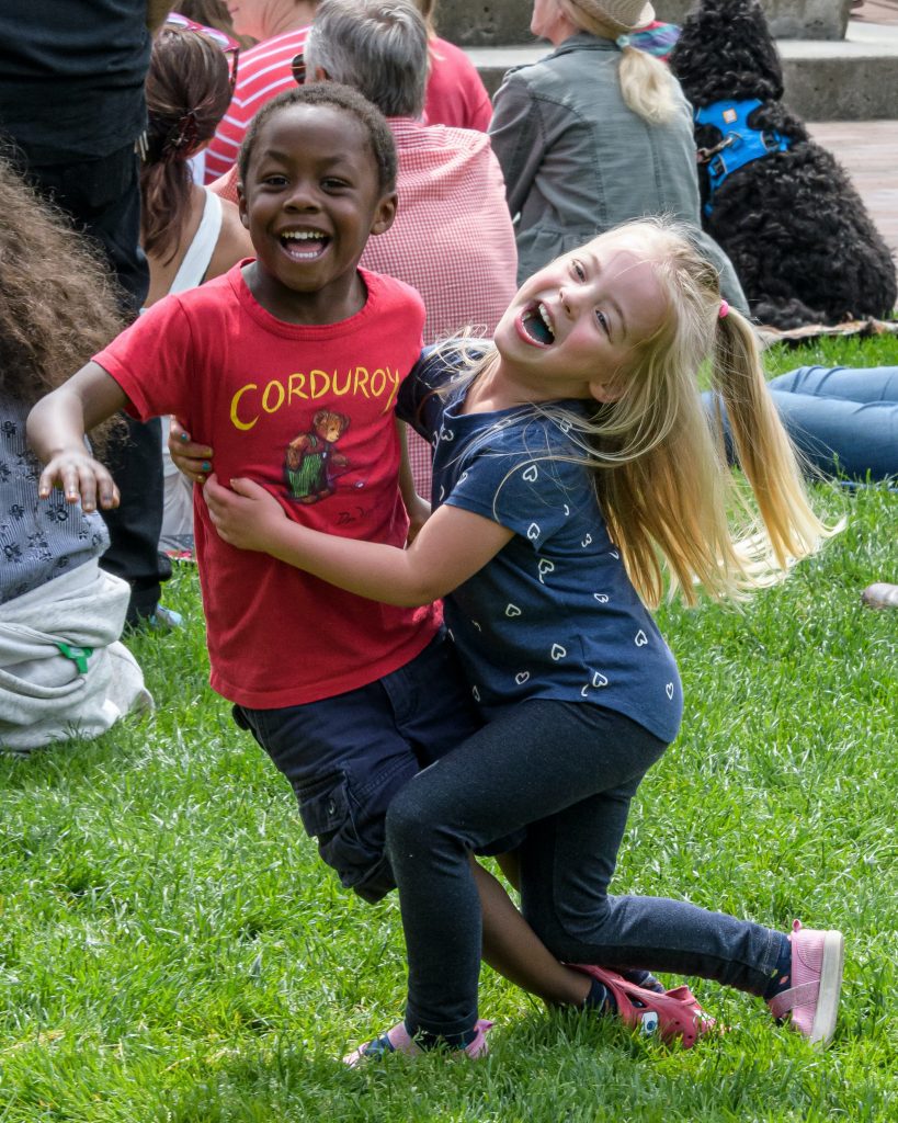 a young boy and girl playing in the grass