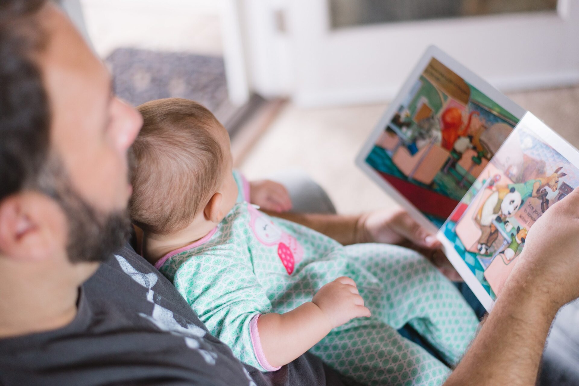 parent reading a picture book to a baby