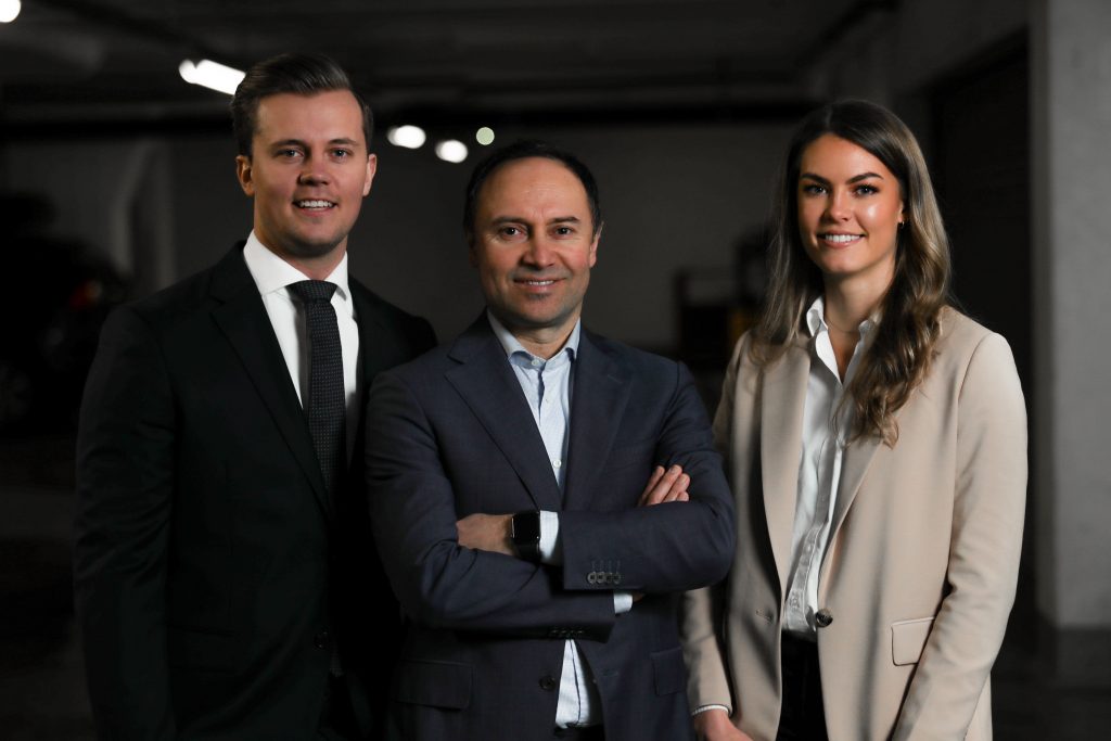 two men and one woman in business attire standing together