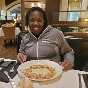 woman smiling in front a fancy meal at a restaurant