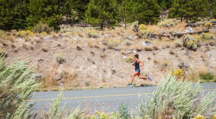 woman running on a road with dusty hillside in the background