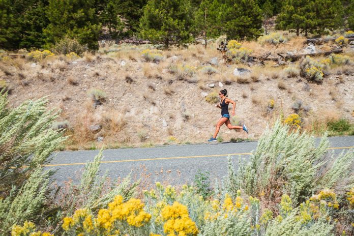 woman running on a road with dusty hillside in the background