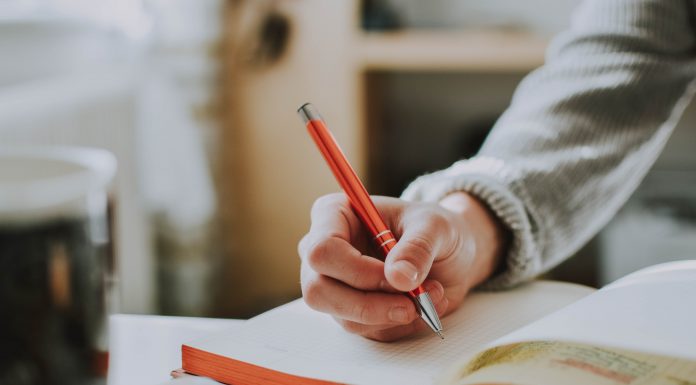 Person's hand about to write in a journal