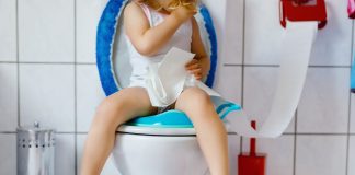 child sitting on a toilet with toilet paper in hand