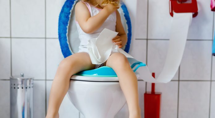 child sitting on a toilet with toilet paper in hand