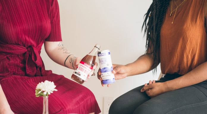 two women sitting together with food and drinks