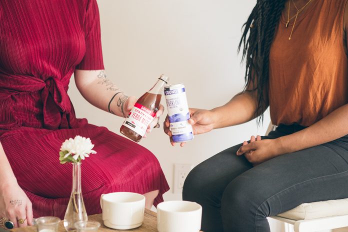 two women sitting together with food and drinks