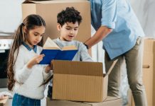 children looking in a moving box with parent in background