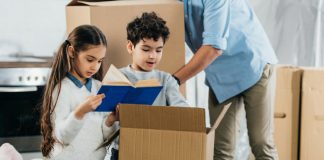 children looking in a moving box with parent in background