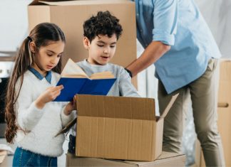 children looking in a moving box with parent in background