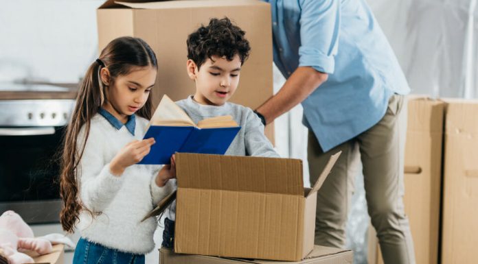 children looking in a moving box with parent in background