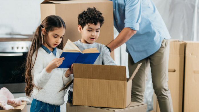 children looking in a moving box with parent in background