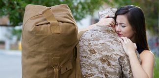 woman hugging a soldier with a military bag