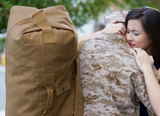 woman hugging a soldier with a military bag