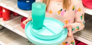 young girl holding colored plates and cups in a store