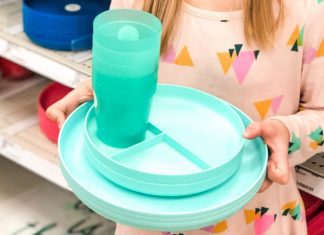 young girl holding colored plates and cups in a store